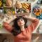 Overhead view of a woman reclining beside a kitchen counter arranged with assorted foods.