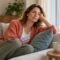 Woman resting on a cream sofa beside a teal cushion and a cup.