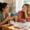 Two women talking together over coffee at a bright table.